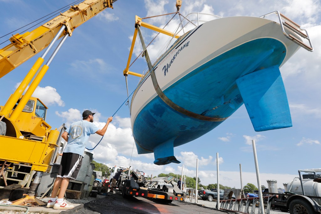 Boat crews were seen pulling a sailboat named Hurricane from the waters of Padanaram Harbor in Dartmouth, Mass., Thursday, Sept. 14, 2023, in preparation for the hurricane. 
