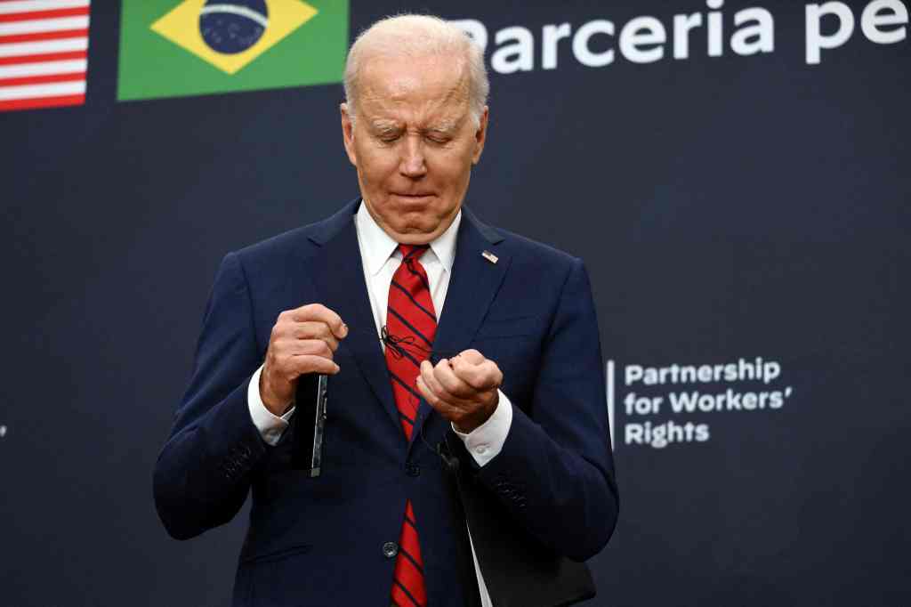 Biden is seen struggling with a chord on his headset during Lula's speech.
